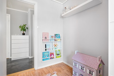 A white room with a pink doll house on the floor