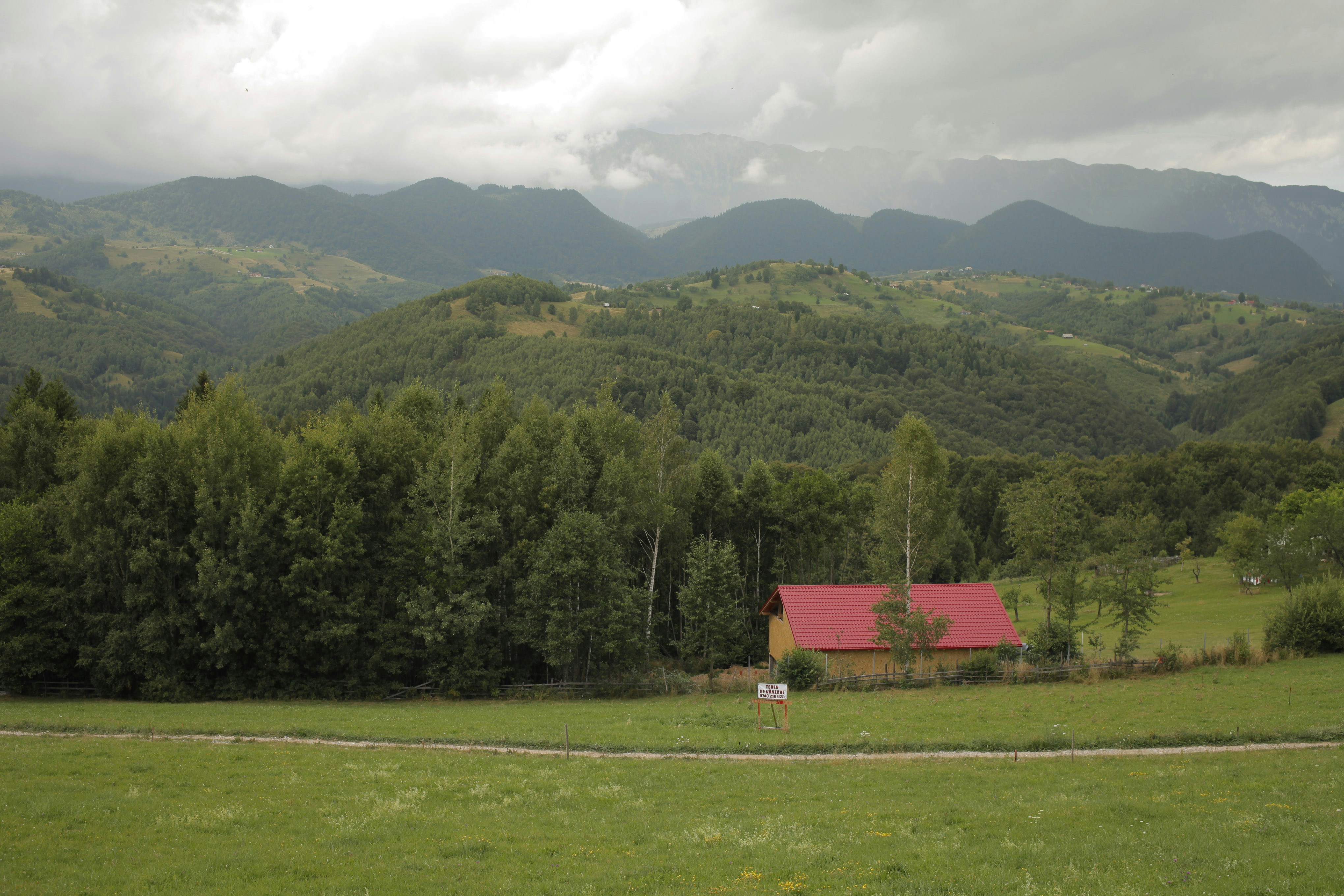 A red house in a green field with mountains in the background