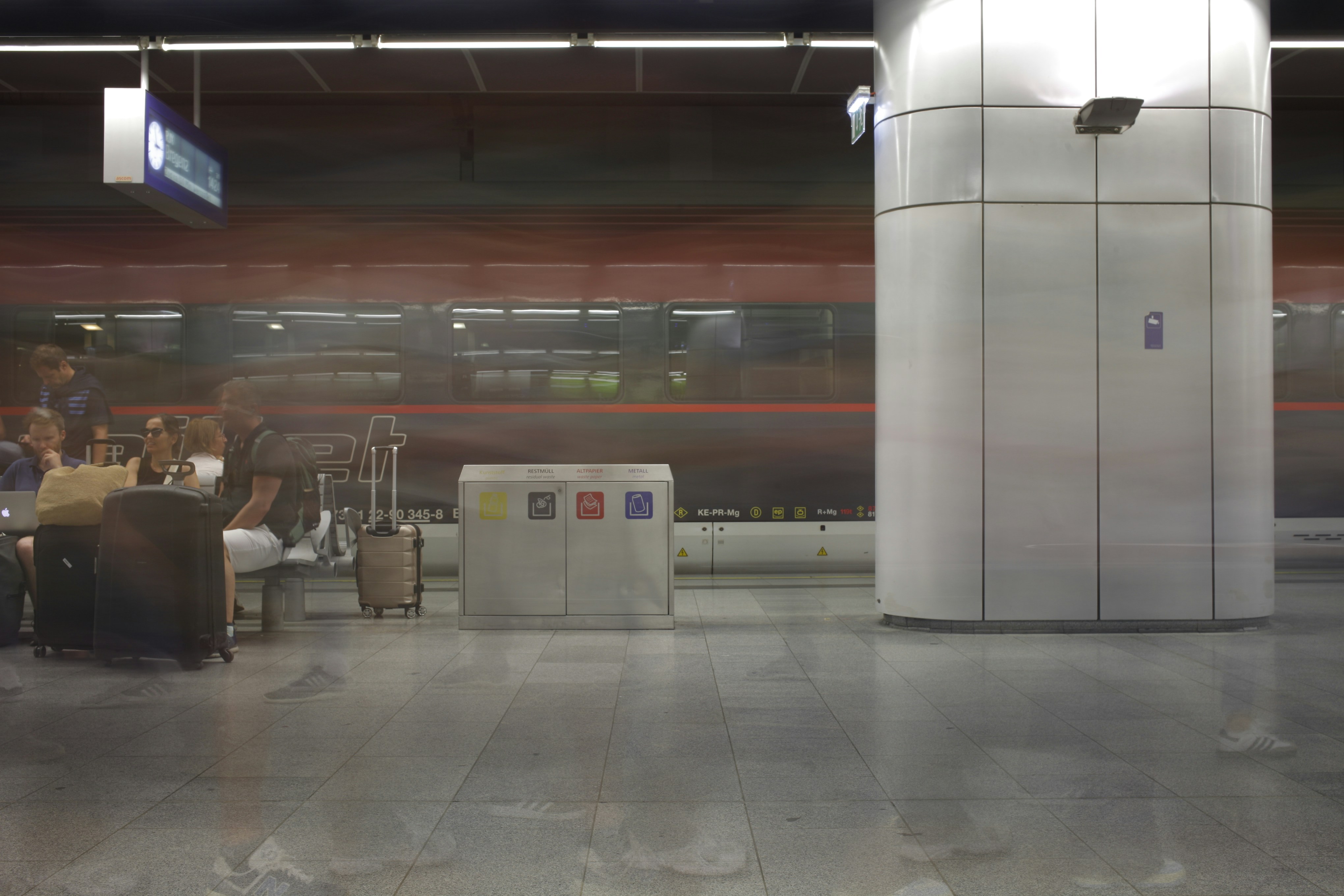 A blurry photo of a train station with people sitting at tables