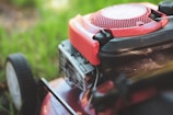 A red lawn mower sitting on top of a lush green field
