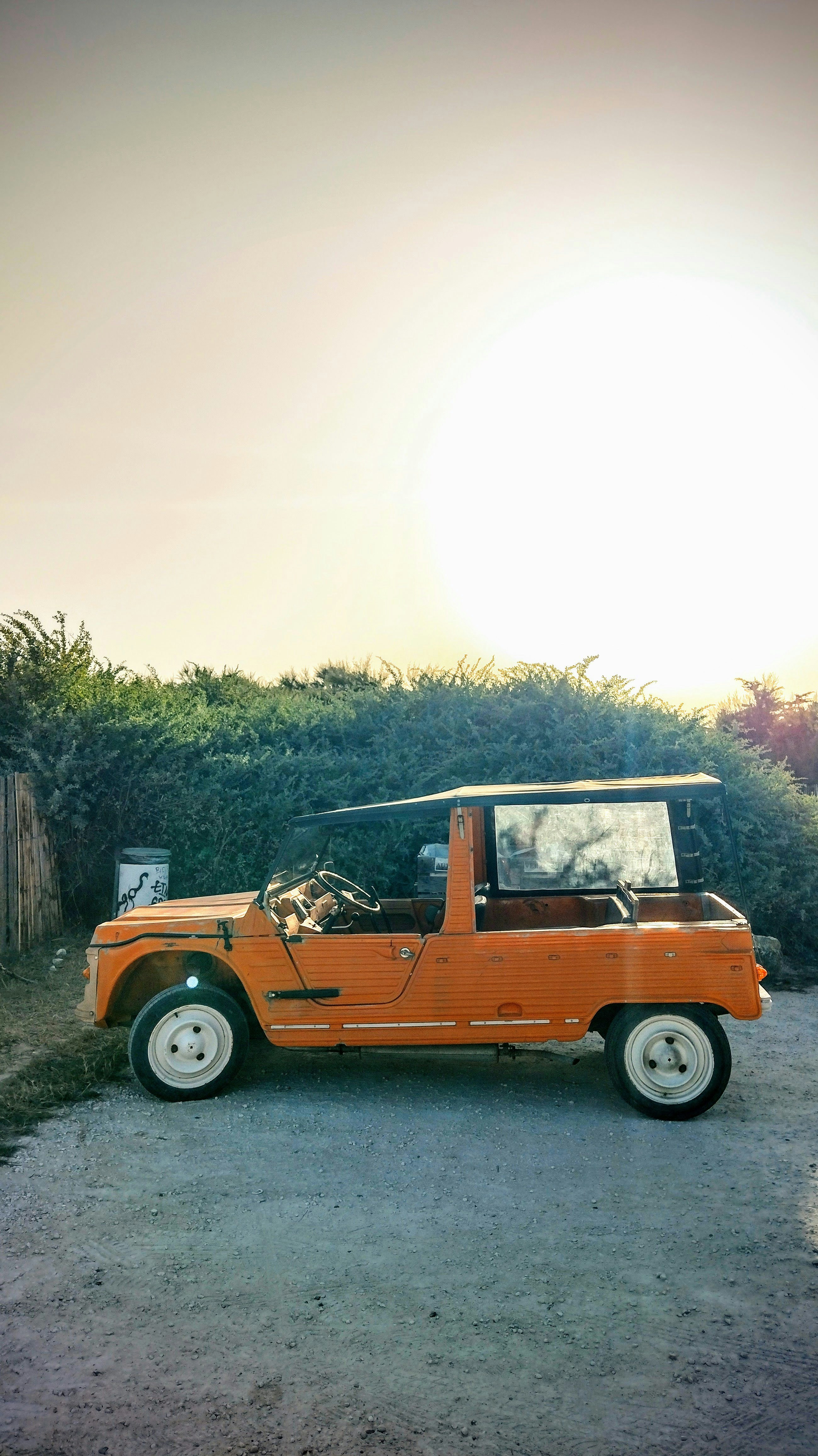 Une jeep orange garée devant une clôture en bois