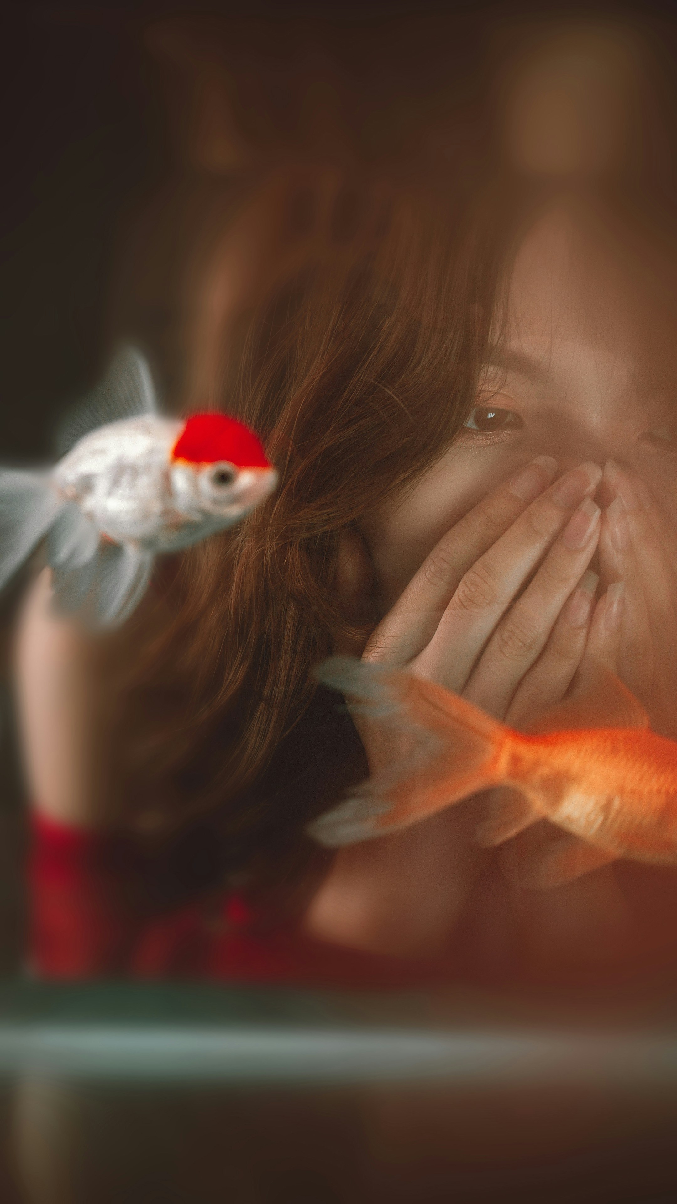 Seorang wanita menutupi wajahnya di sebelah ikan mas