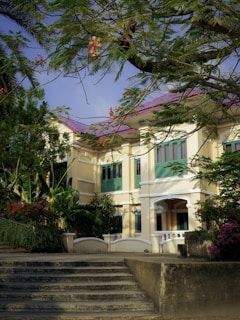 A large white house with green shutters and trees