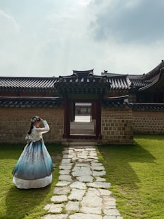 A woman in a blue dress standing in front of a building