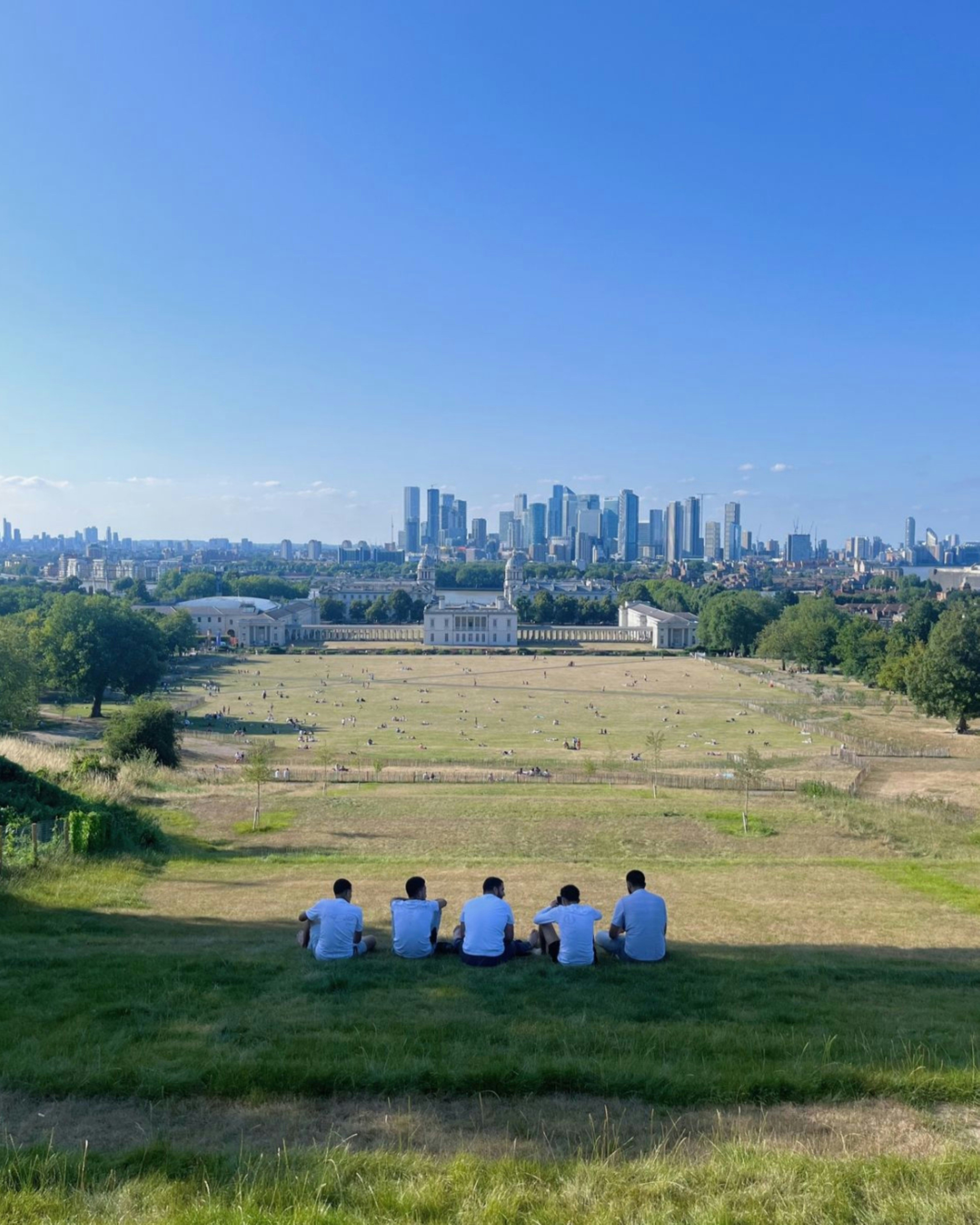 A group of people sitting on top of a lush green field