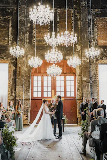 A bride and groom standing in front of a chandelier