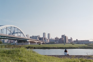 A person sitting on a bench near a river and a bridge
