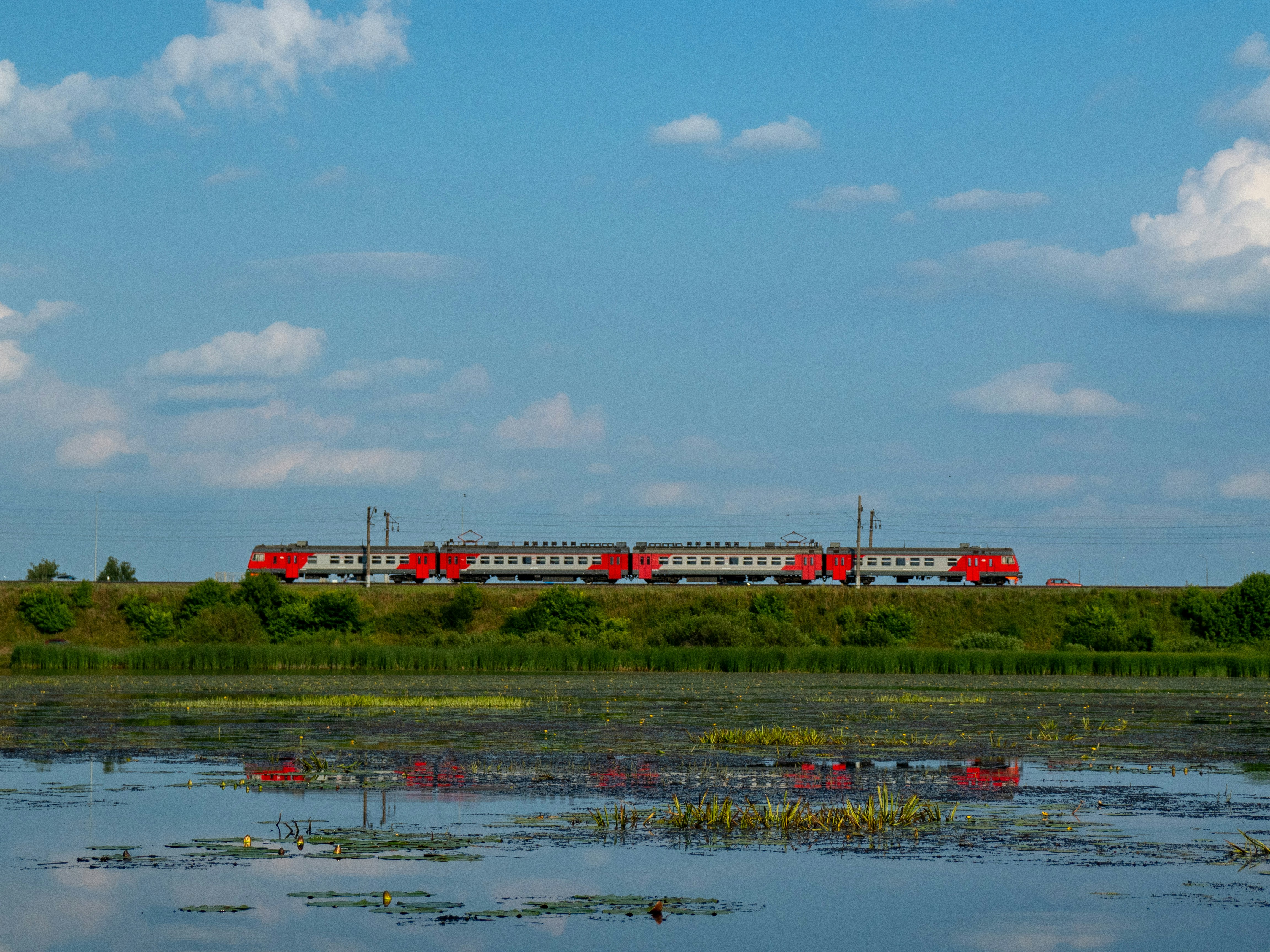 A red train traveling through a lush green countryside