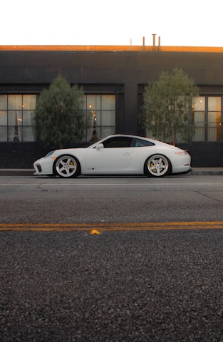 A white sports car parked in front of a building