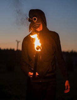 A person wearing a mask and holding a lit cigarette