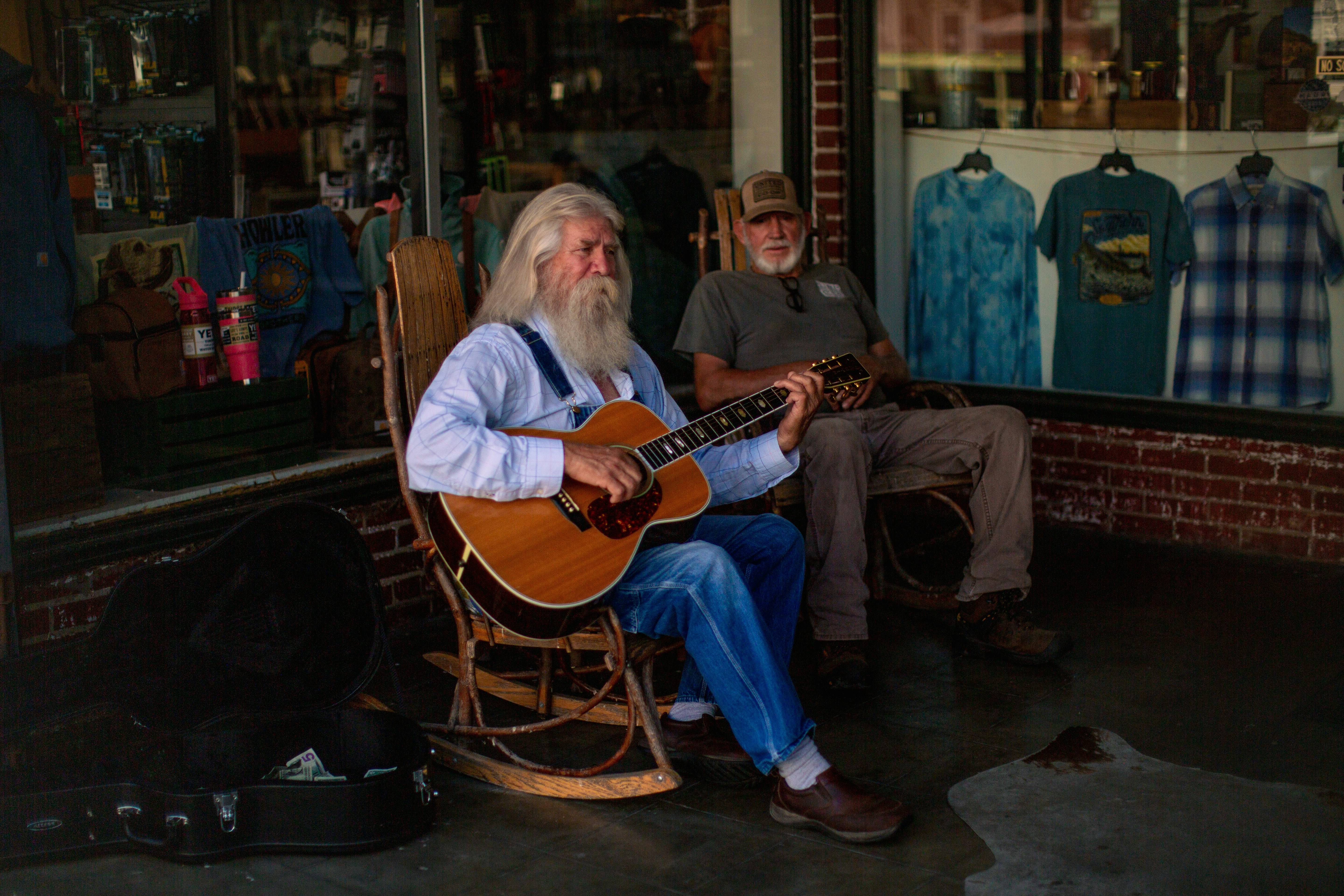 A man sitting in a rocking chair playing a guitar photo – Free Man ...