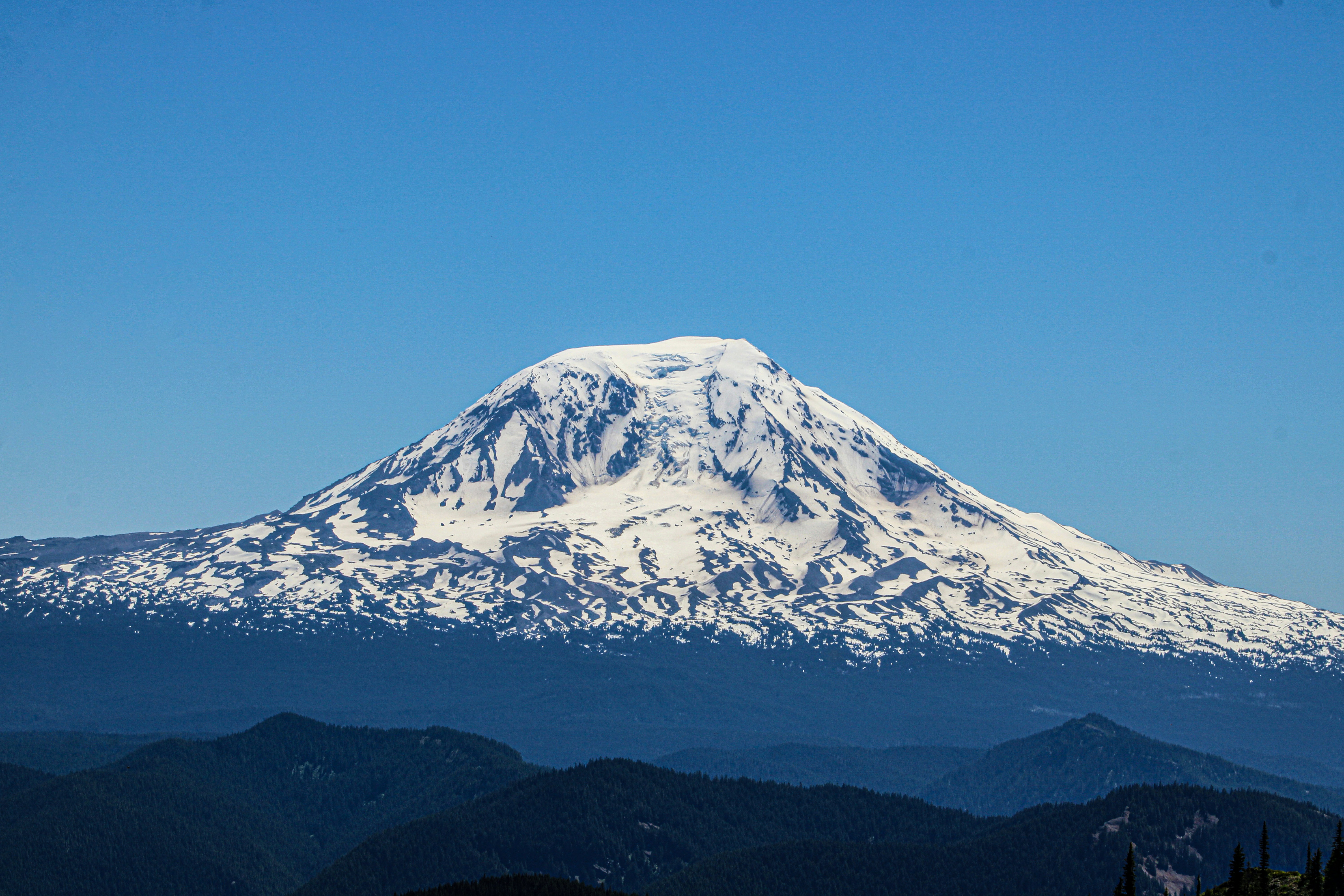 A snow covered mountain in the middle of a blue sky