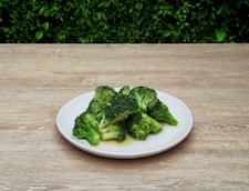 A plate of broccoli on a wooden table