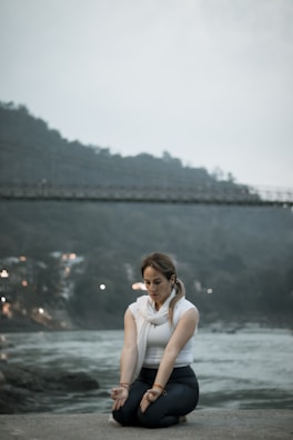 A woman sitting on the ground in front of a river