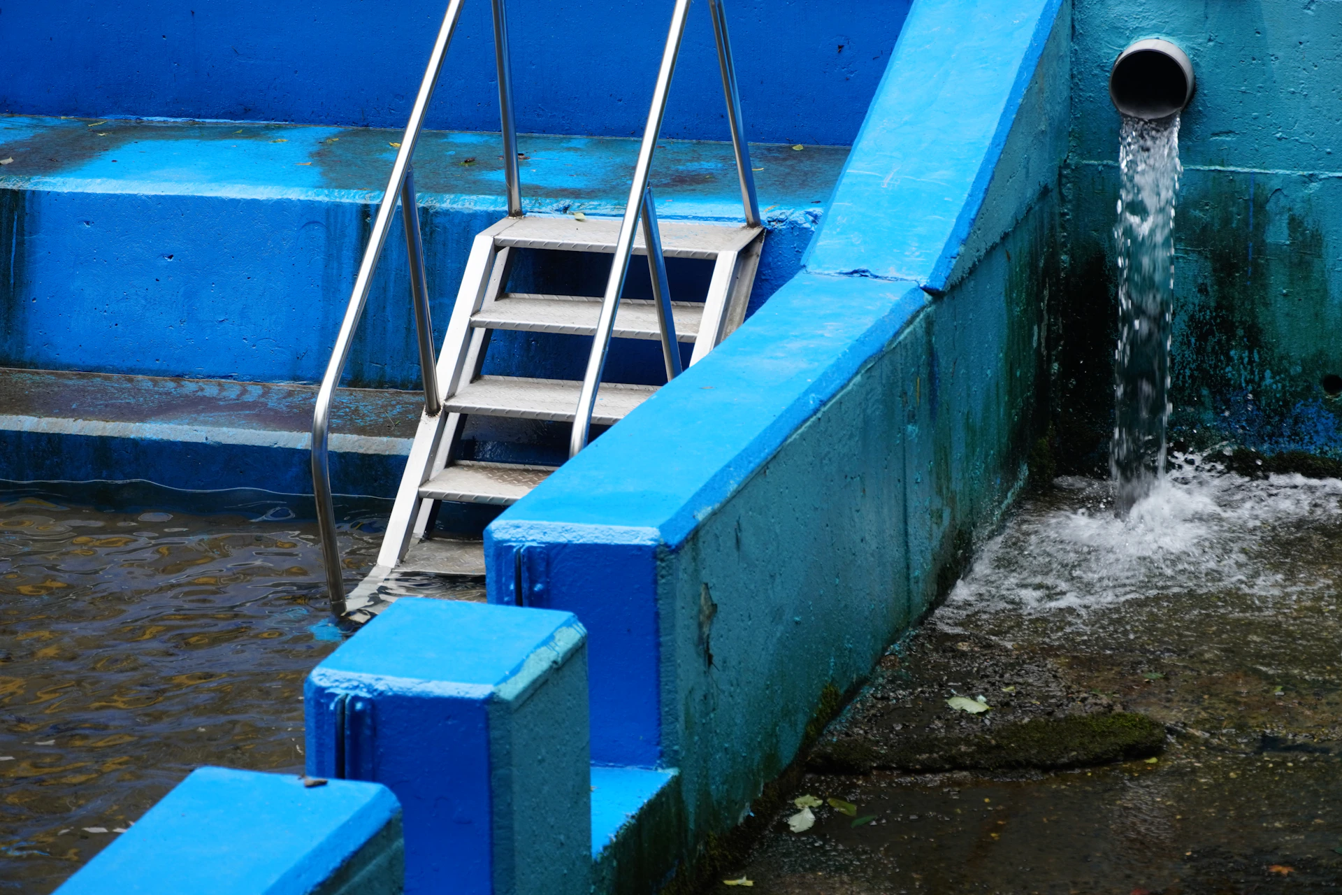 A blue boat with steps going down the side of it