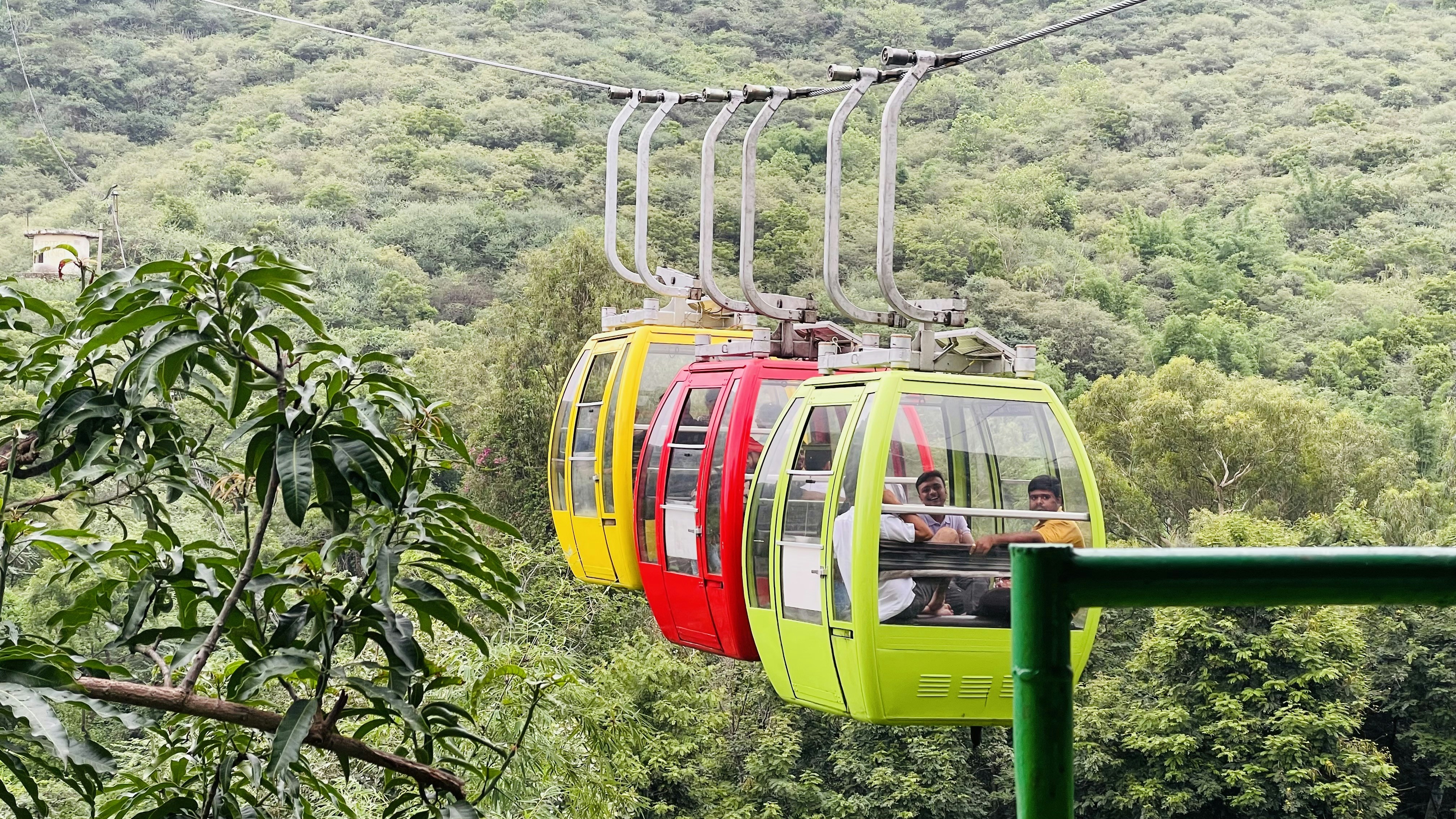 A colorful cable car going over a lush green forest