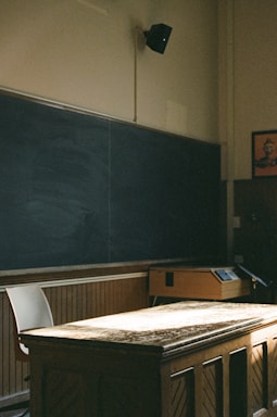 An empty classroom with a blackboard and desk
