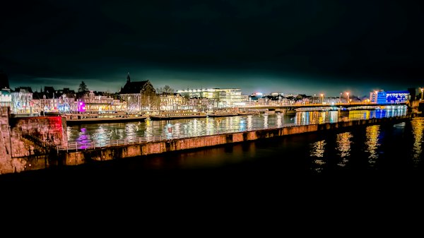 A night time view of a city with a river running through it — Maastricht, Netherlands