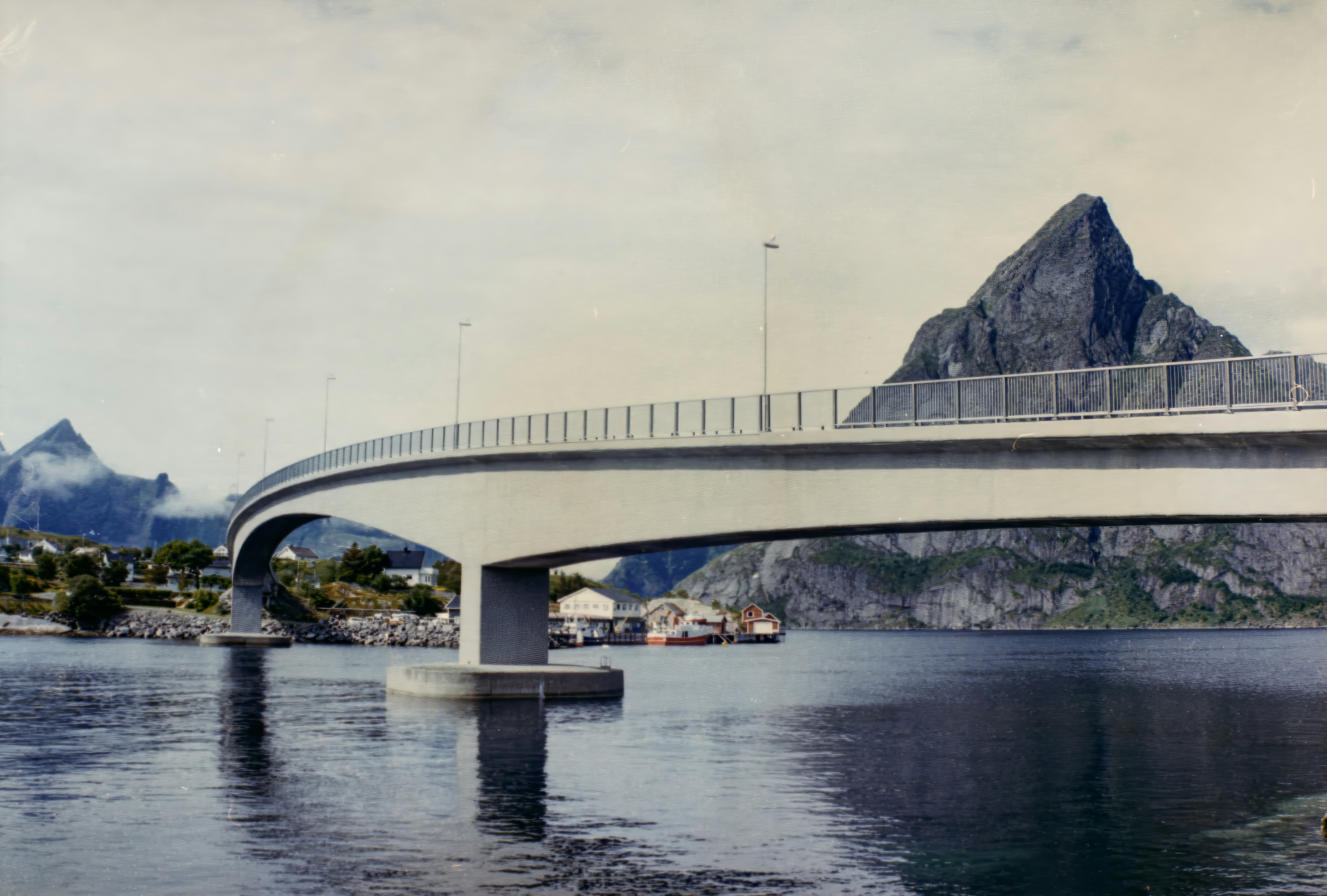 A bridge over a body of water with mountains in the background
