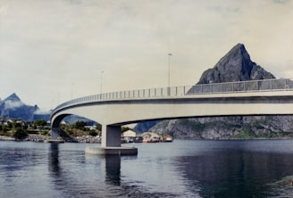 A bridge over a body of water with mountains in the background