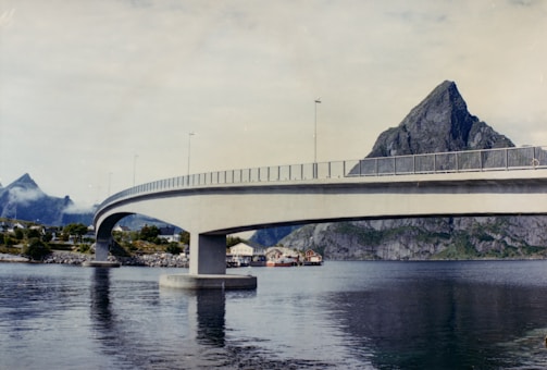 A bridge over a body of water with mountains in the background