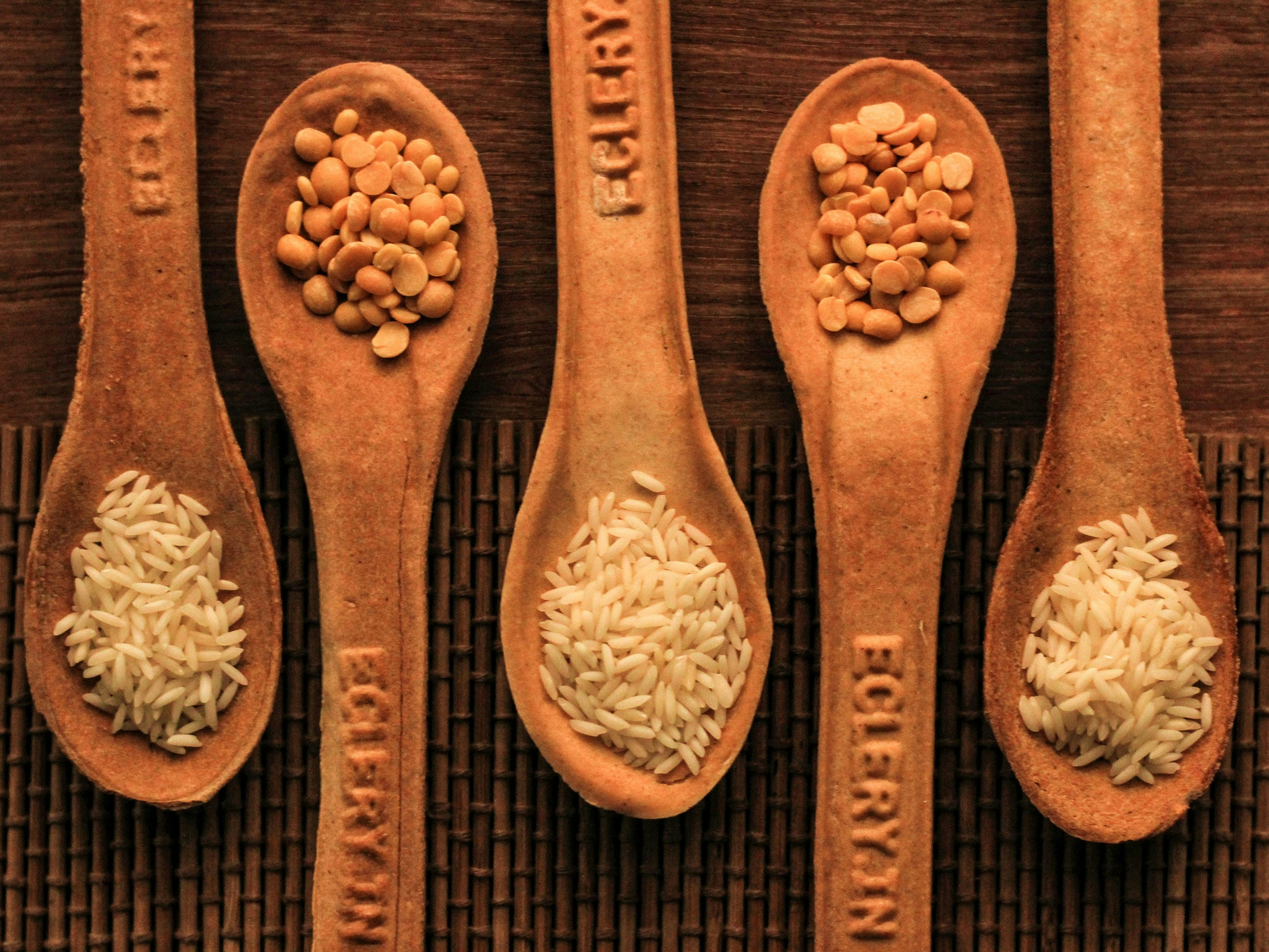 Five wooden spoons filled with rice and beans