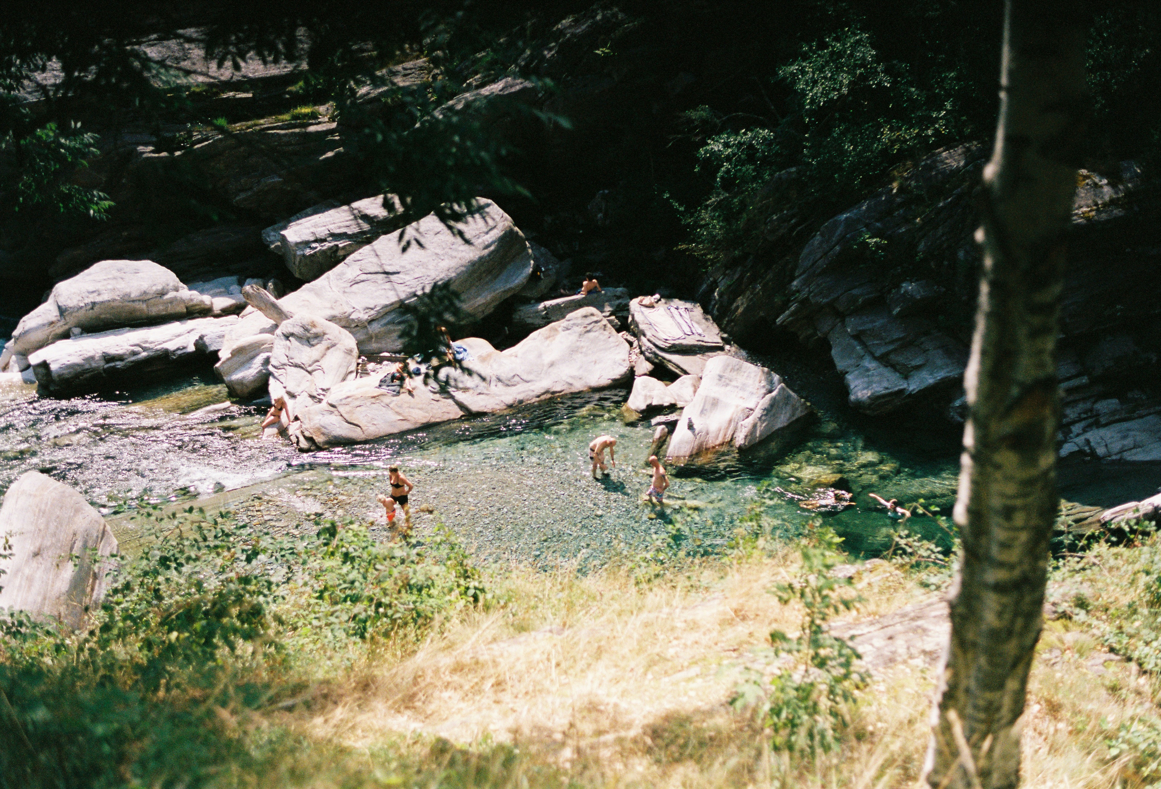 A group of people standing in a river next to rocks