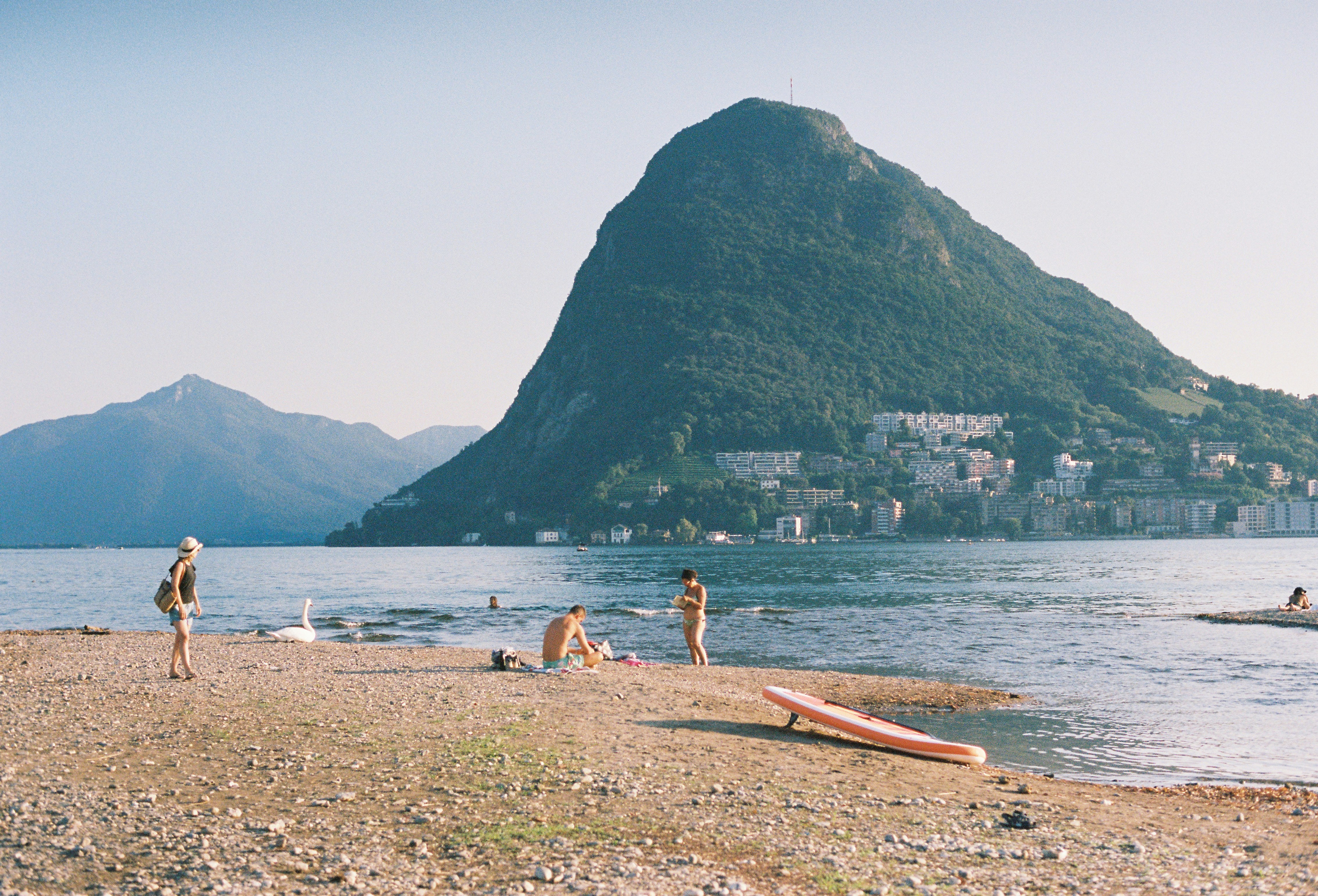 A group of people standing on top of a beach next to a body of water
