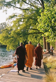 A group of people walking down a wooden walkway next to a body of water