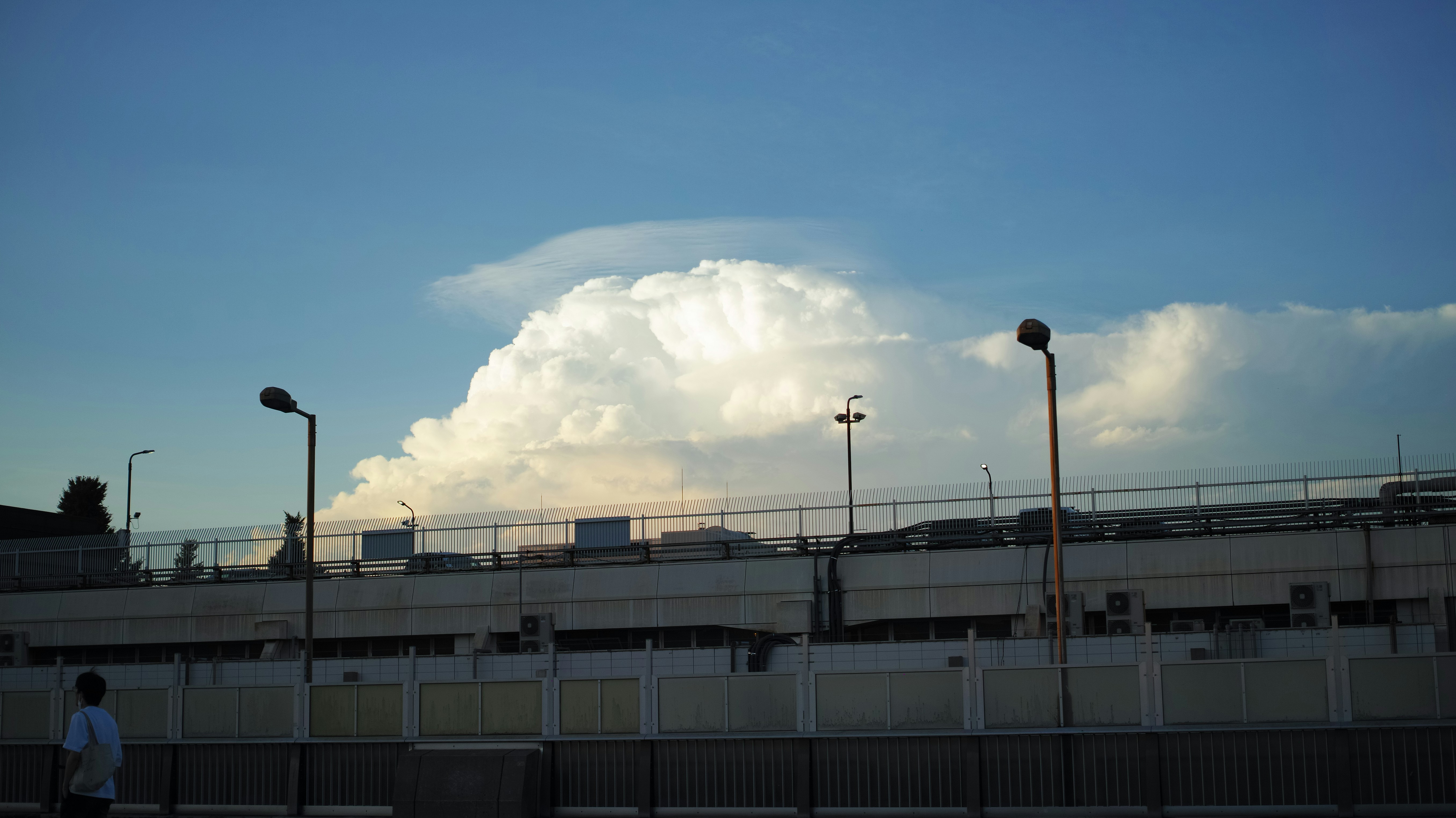 A large cloud is in the sky over a parking lot