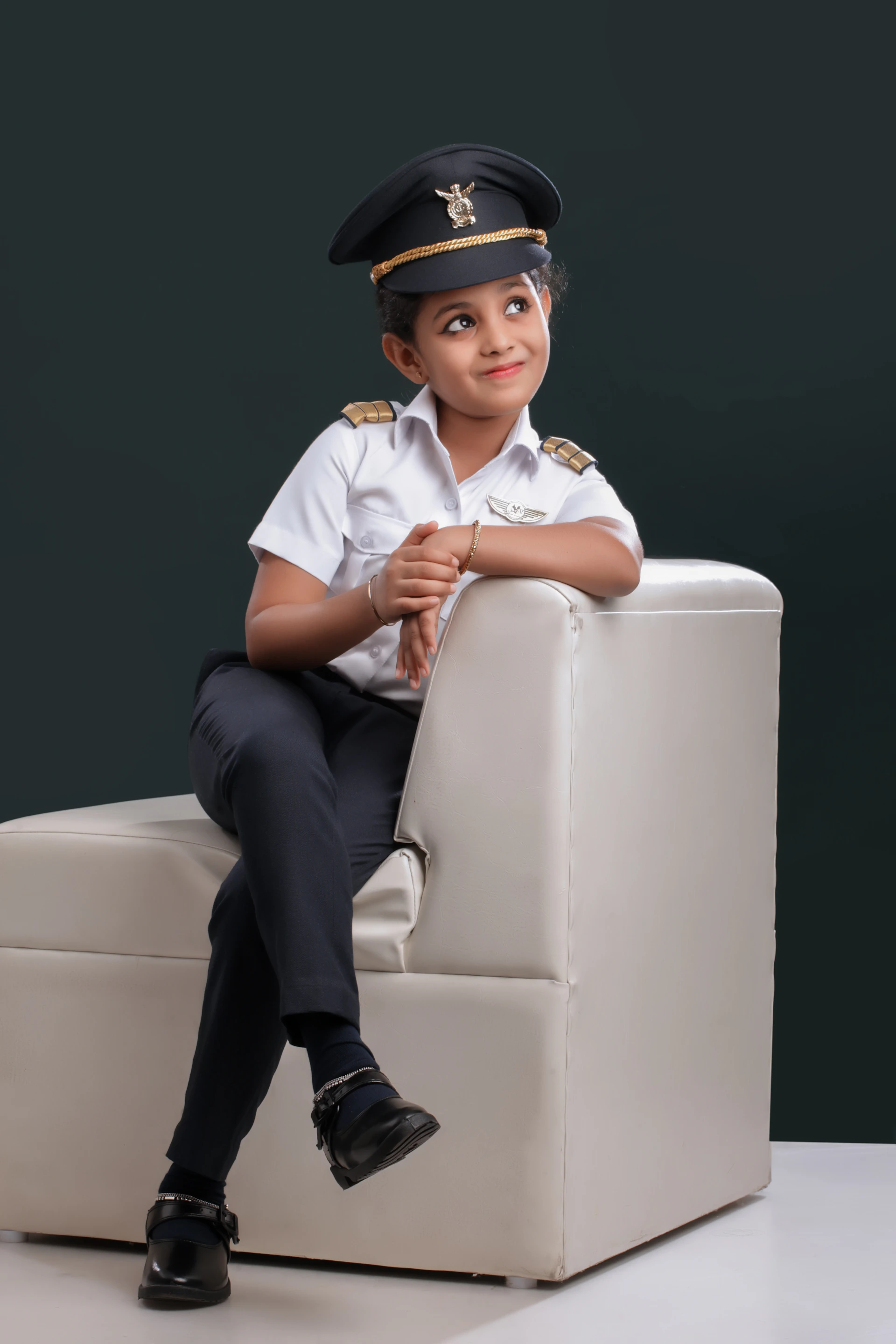 A little boy in a uniform sitting on a chair