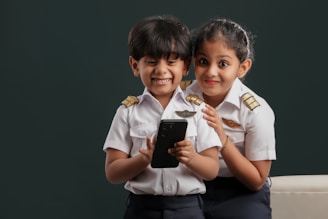 Two young children dressed in uniforms holding a tablet