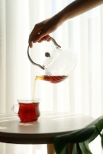 A person pouring tea into a cup on a table