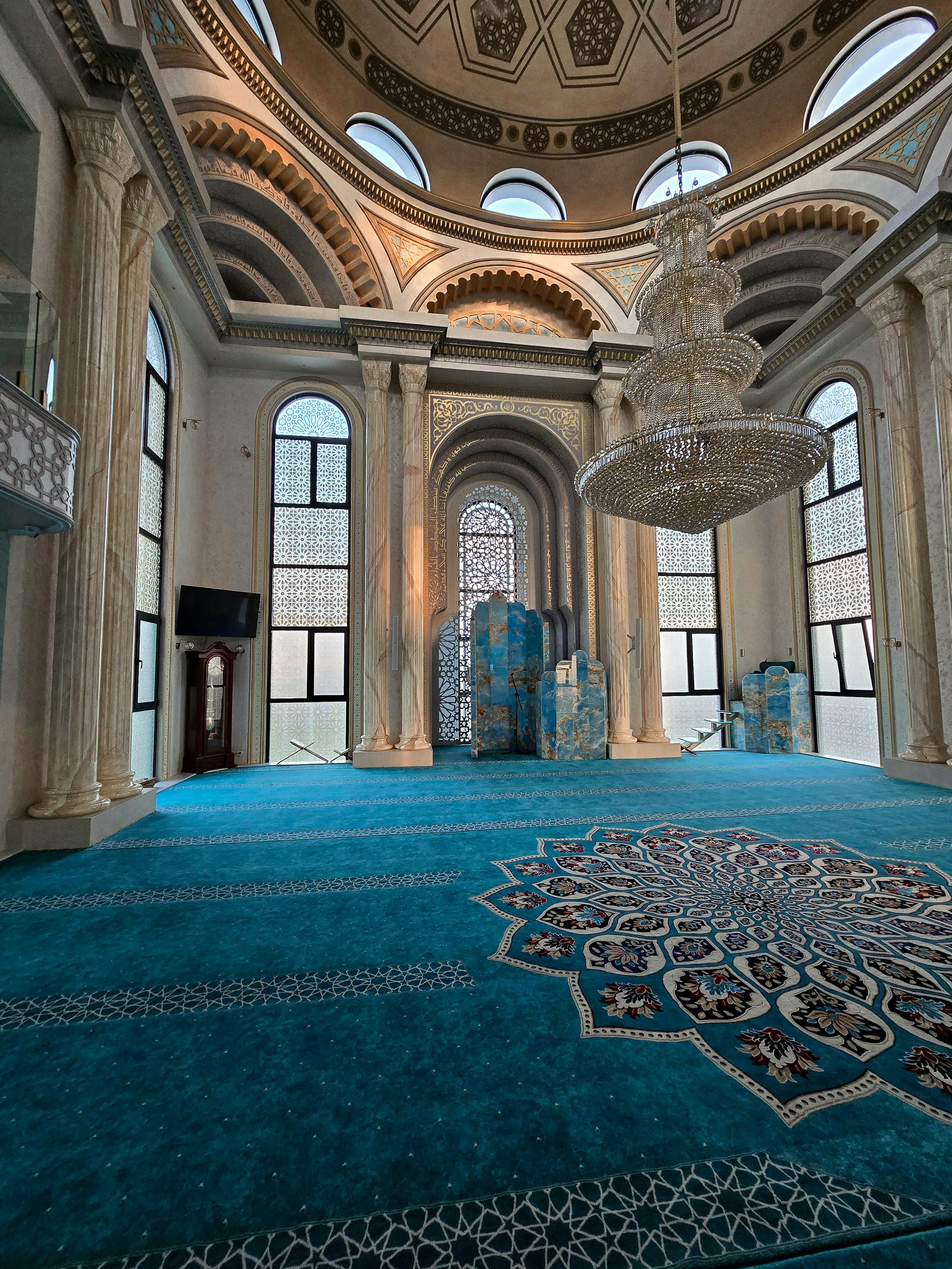 Ein großer Raum mit blauem Teppich und Kronleuchter