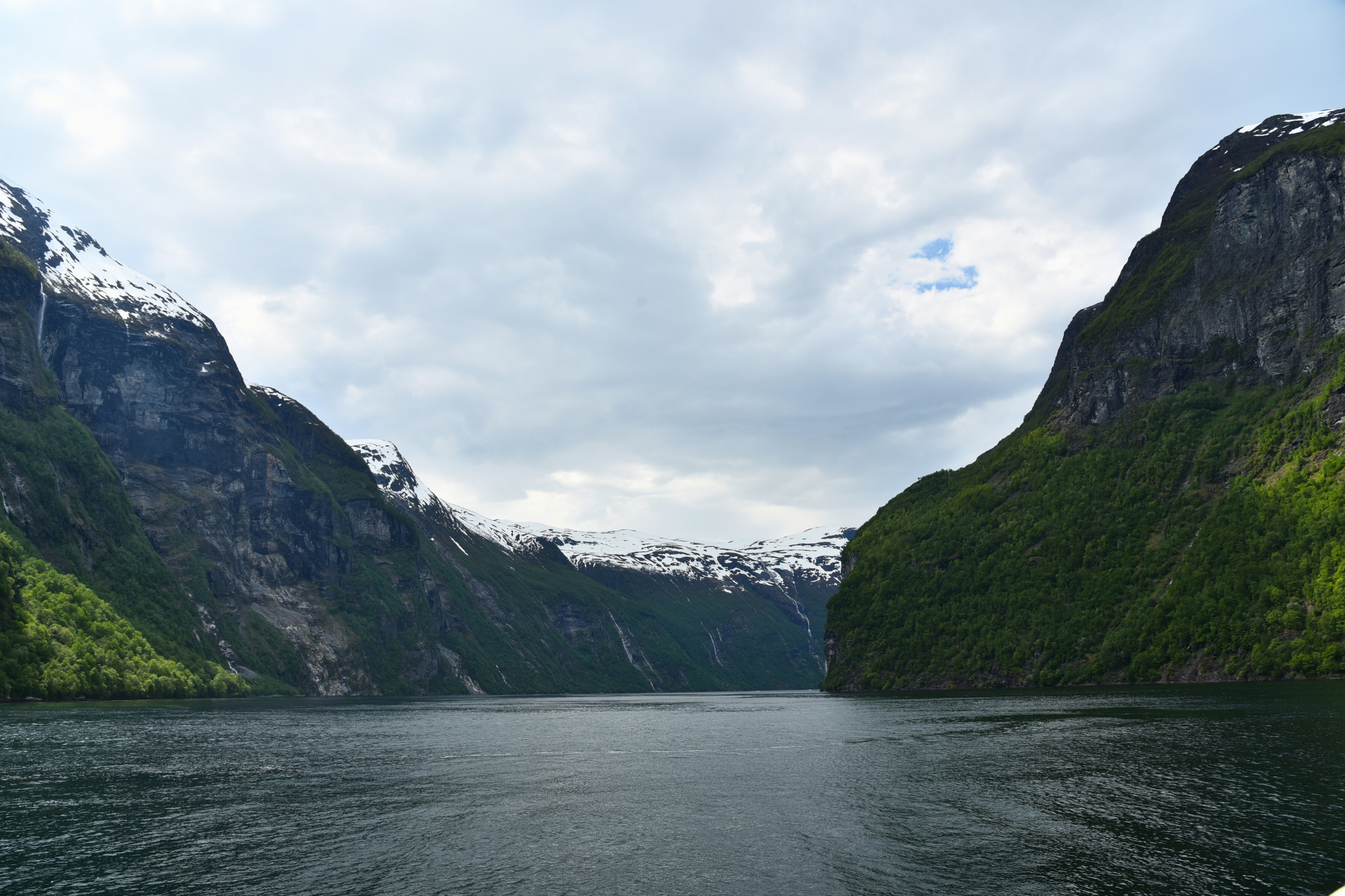 A body of water surrounded by mountains under a cloudy sky