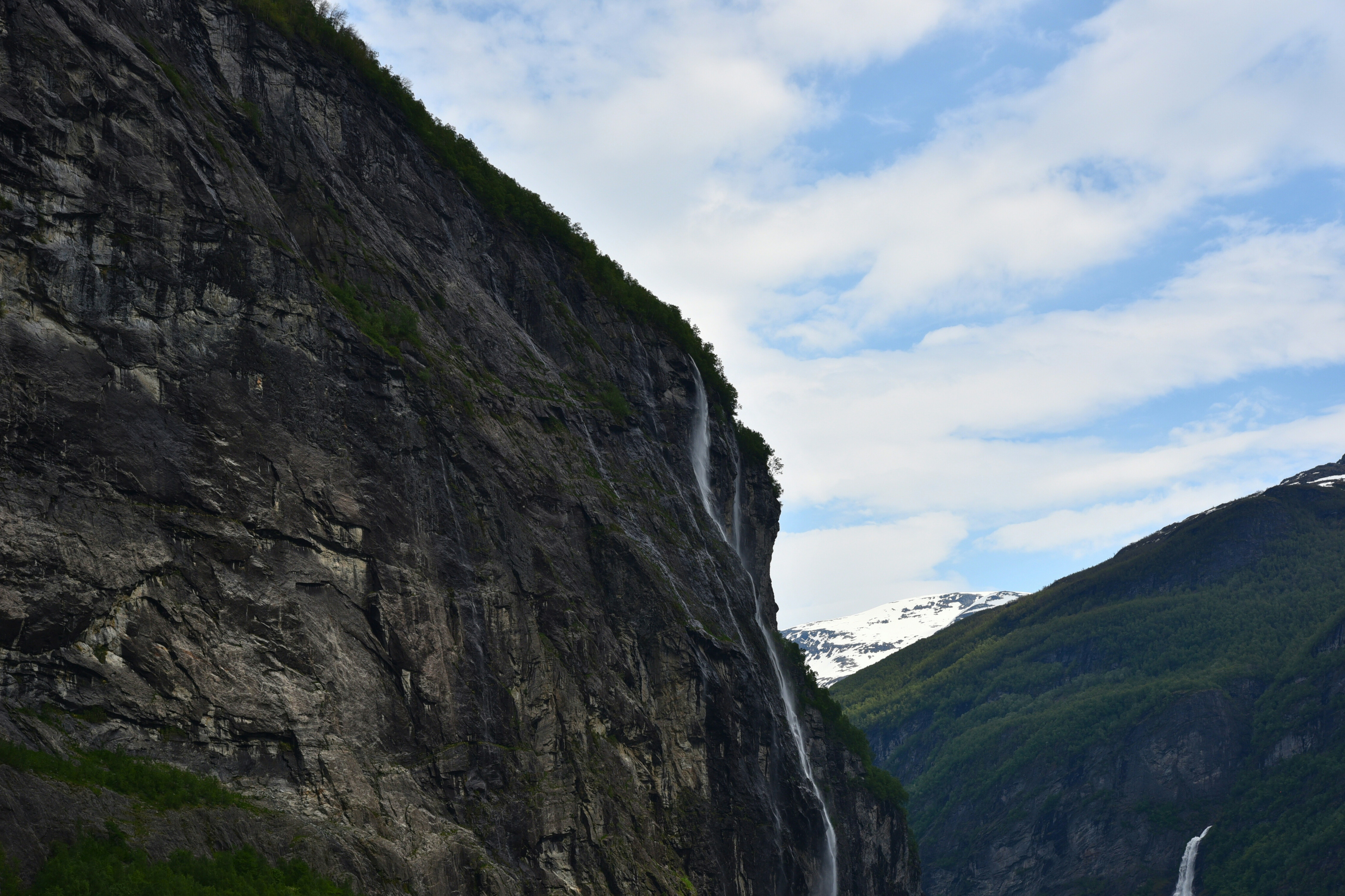A long road with a waterfall on the side of it