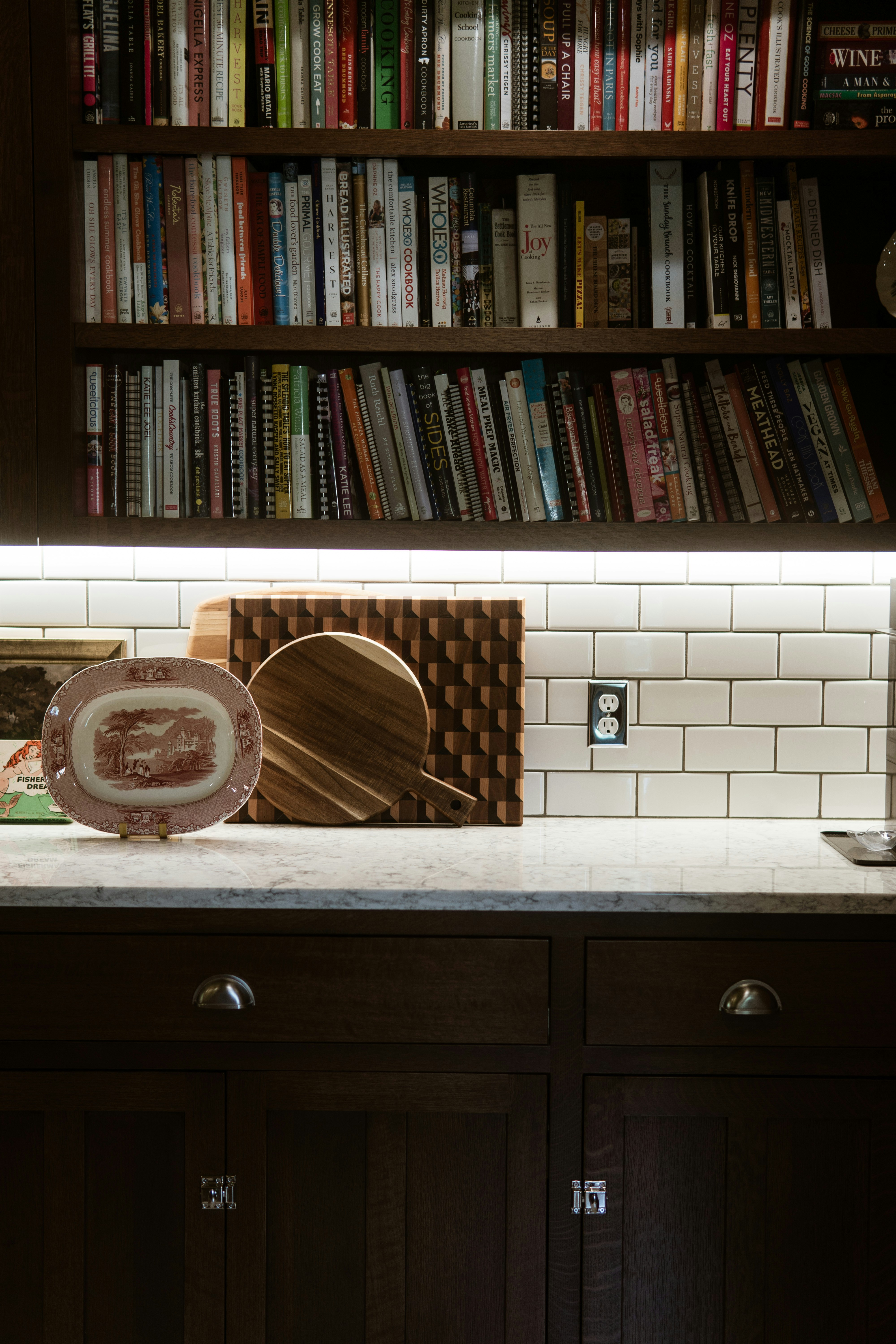 A kitchen counter with a microwave and bookshelf in the background
