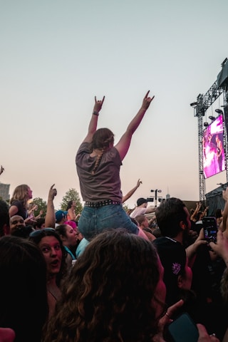 A crowd of people at a concert with their arms in the air