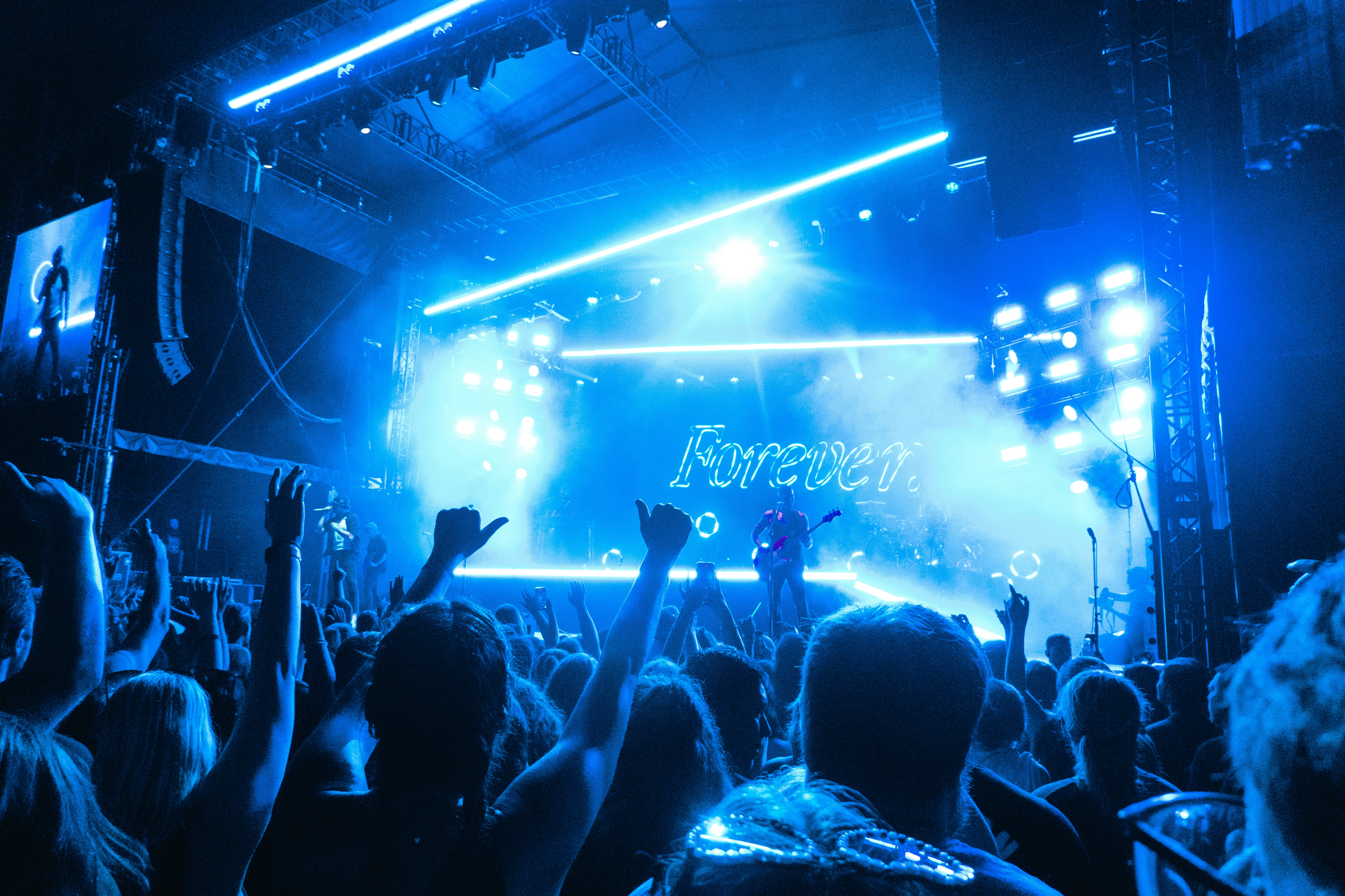 A crowd of people at a concert with their hands in the air