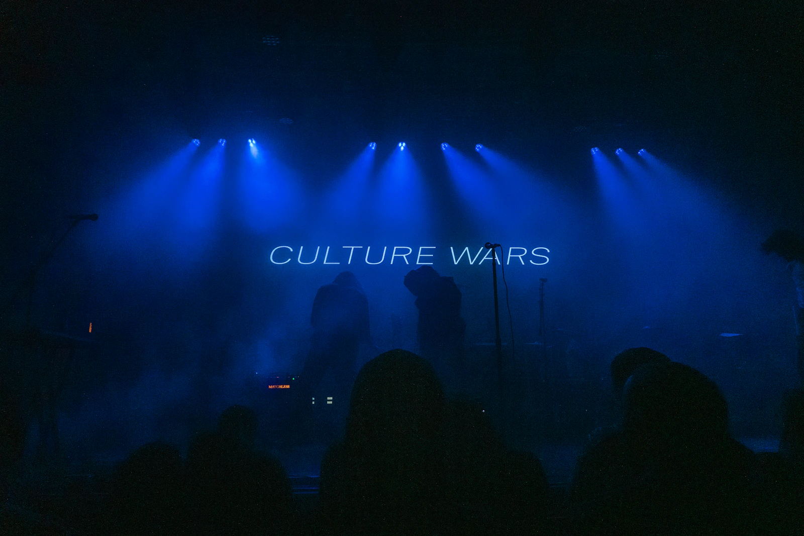 Artists performing on stage beneath concert lights
