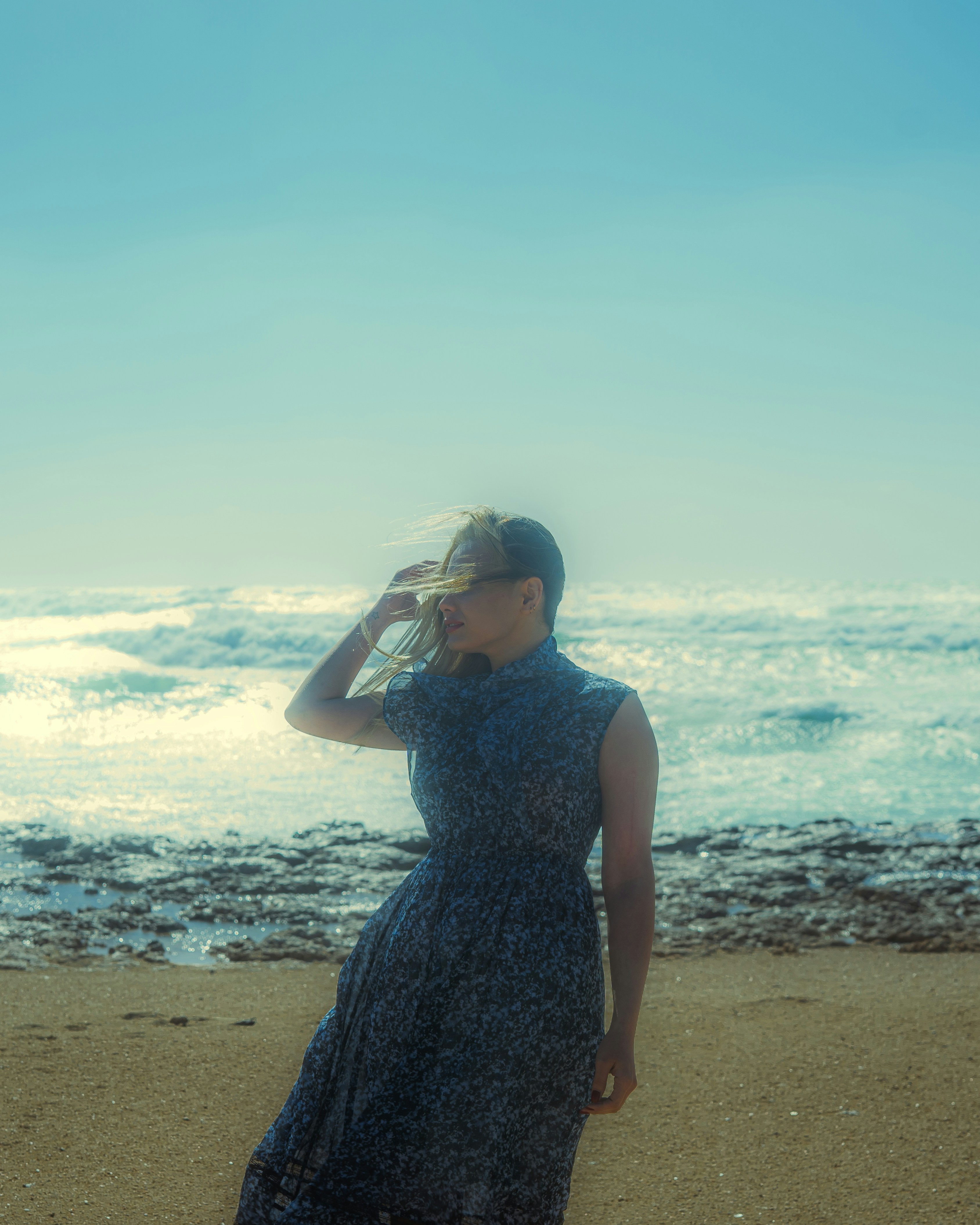 A woman standing on a beach next to the ocean