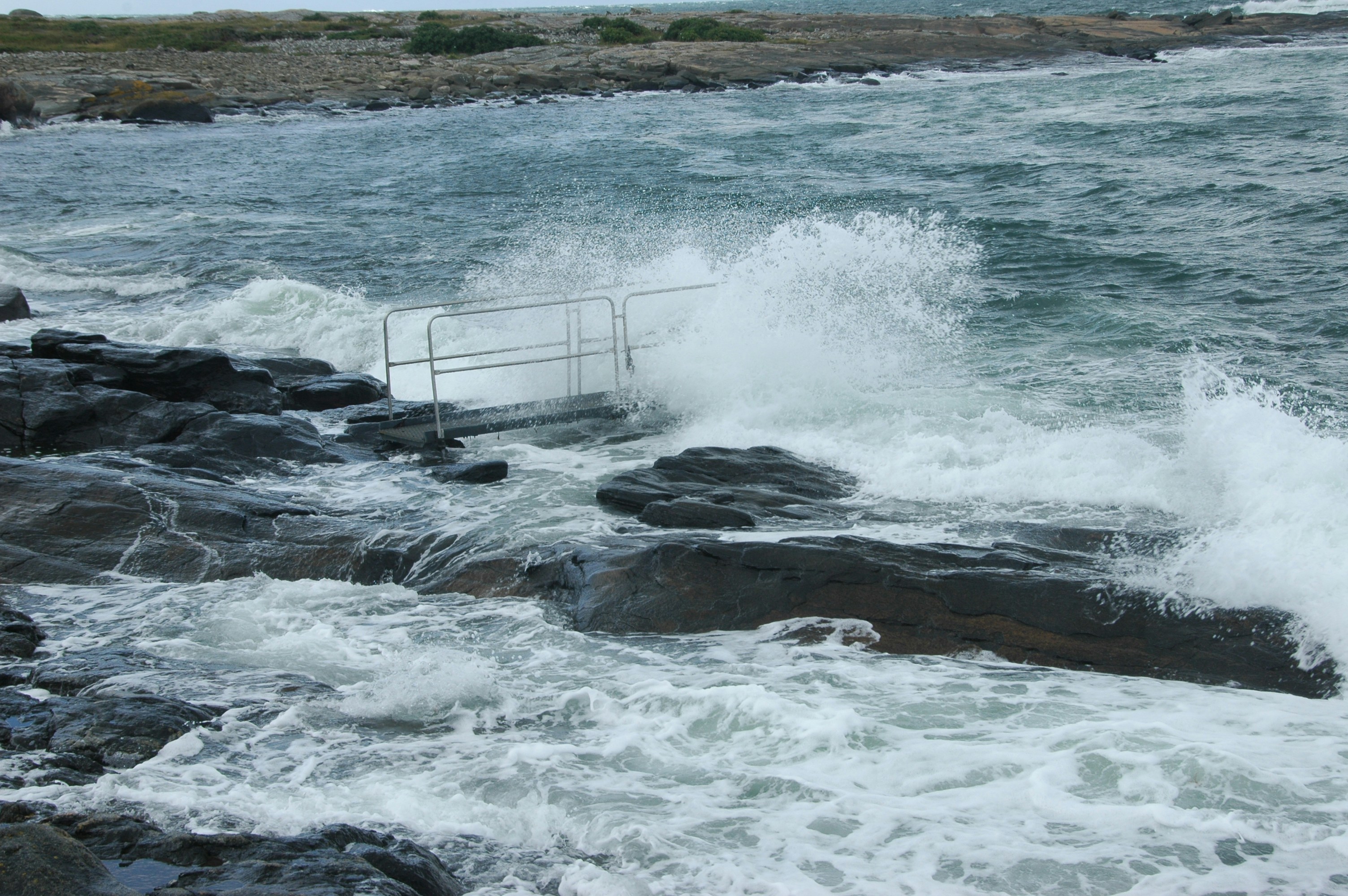 A person standing on a rocky shore next to a body of water