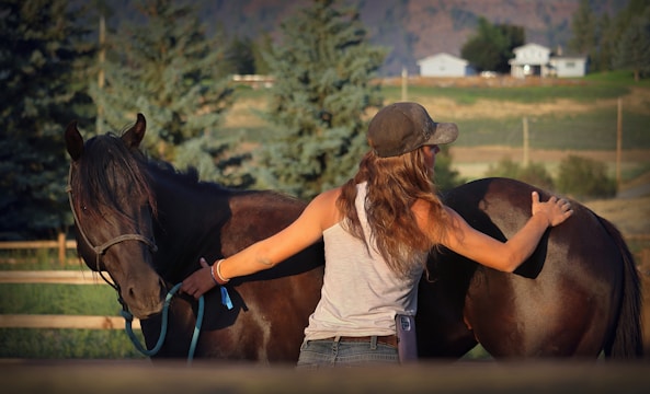 A woman standing next to a brown horse