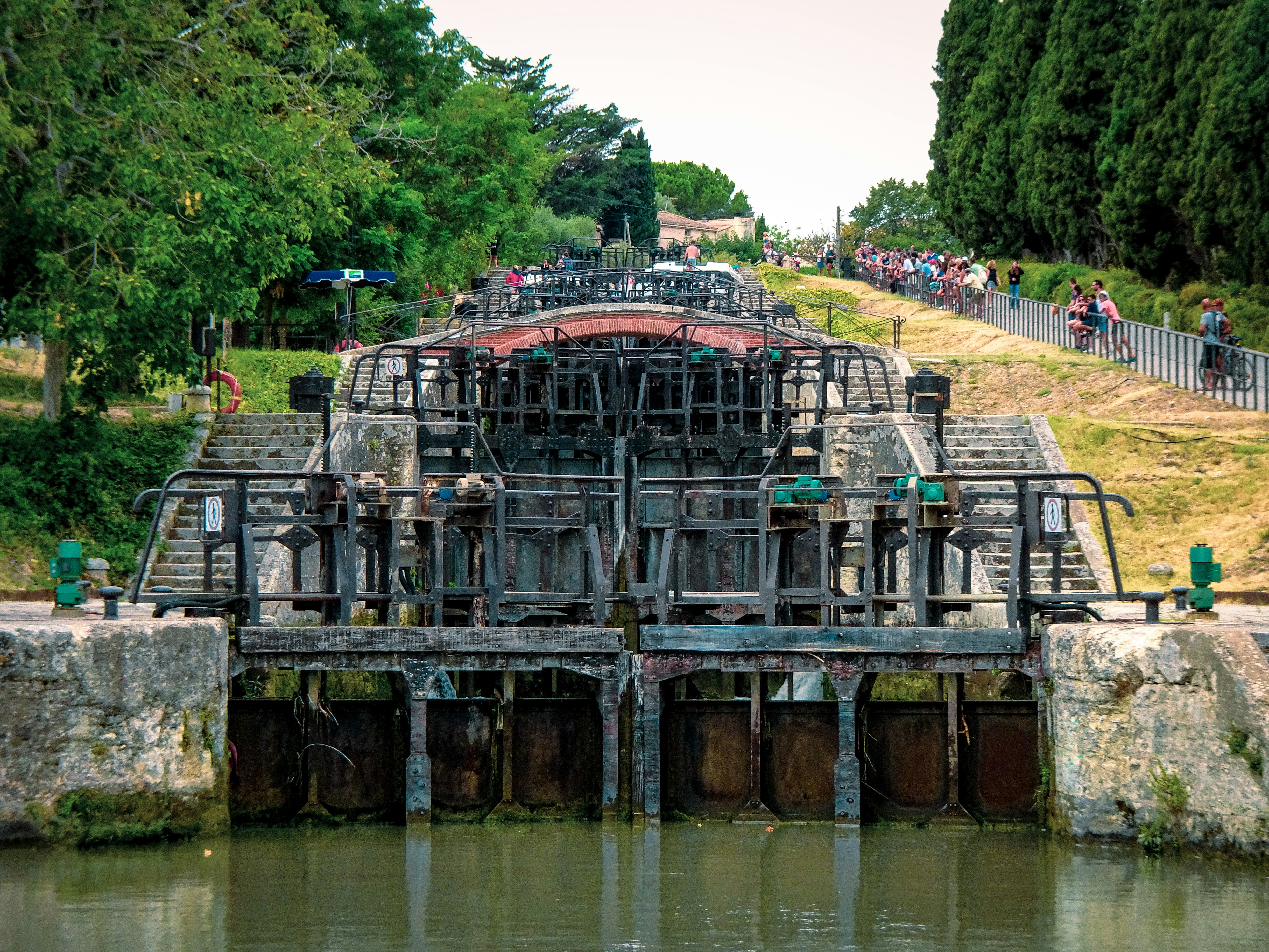 A large structure sitting on top of a river next to a lush green hillside