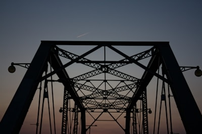 A view of a bridge with a plane flying over it