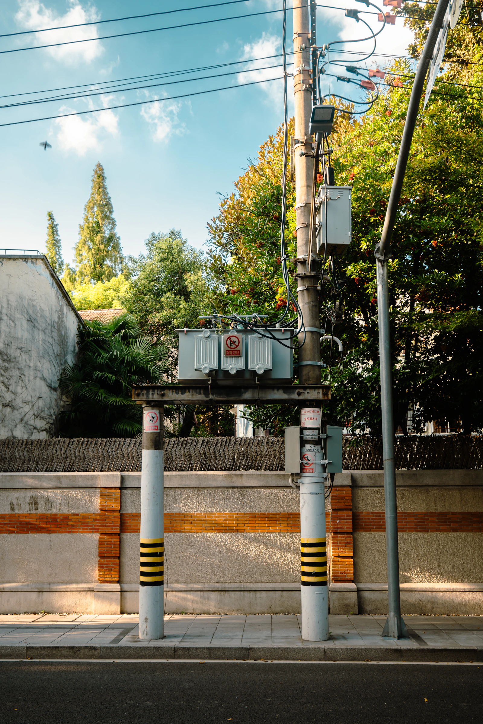 Distribution transformer at an electrical substation — oil-immersed three-phase transformer with high-voltage bushings and radiator cooling fins