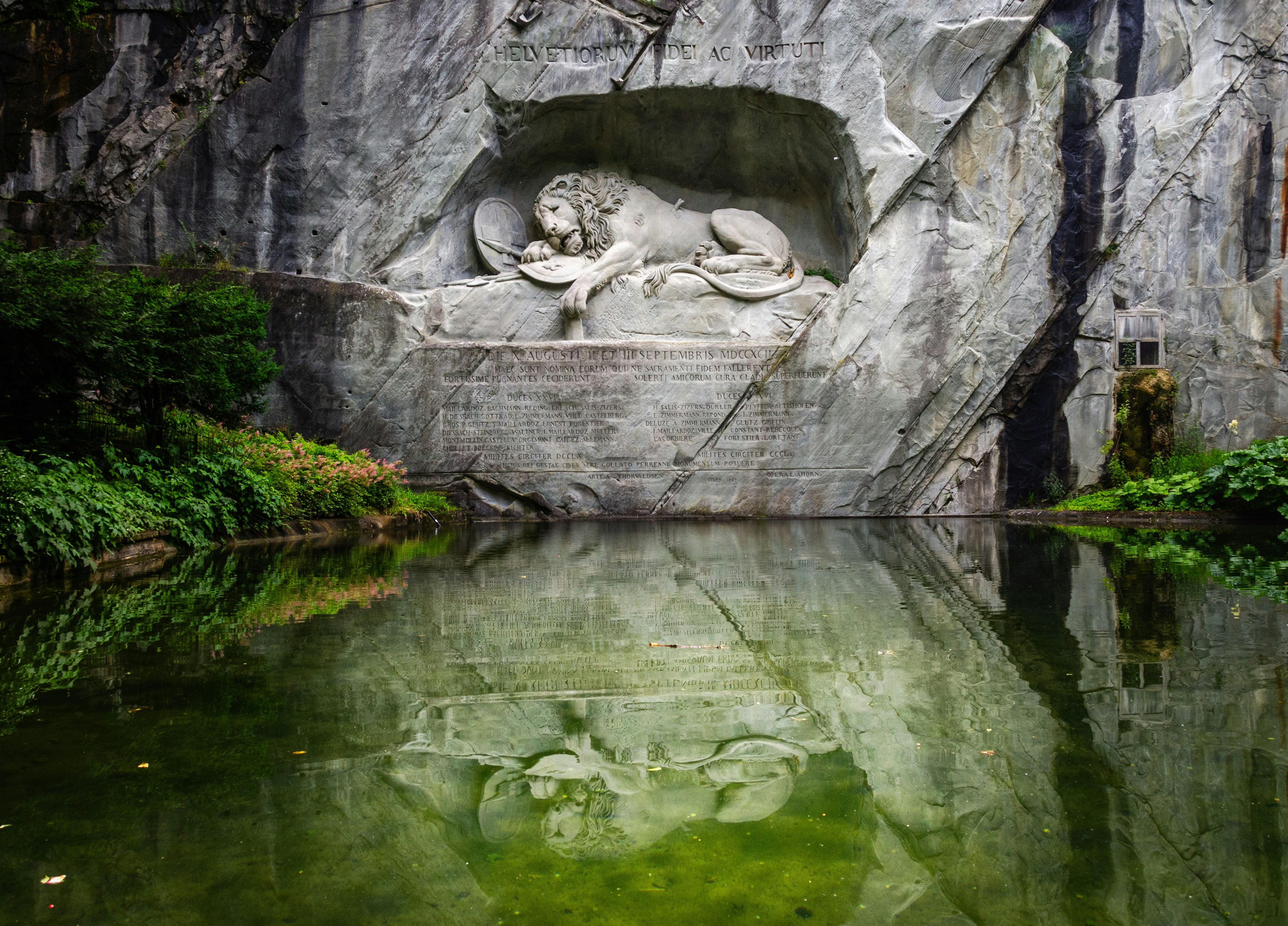 Die Statue eines Löwen, der sich auf einem Felsen neben einem Gewässer ausruht