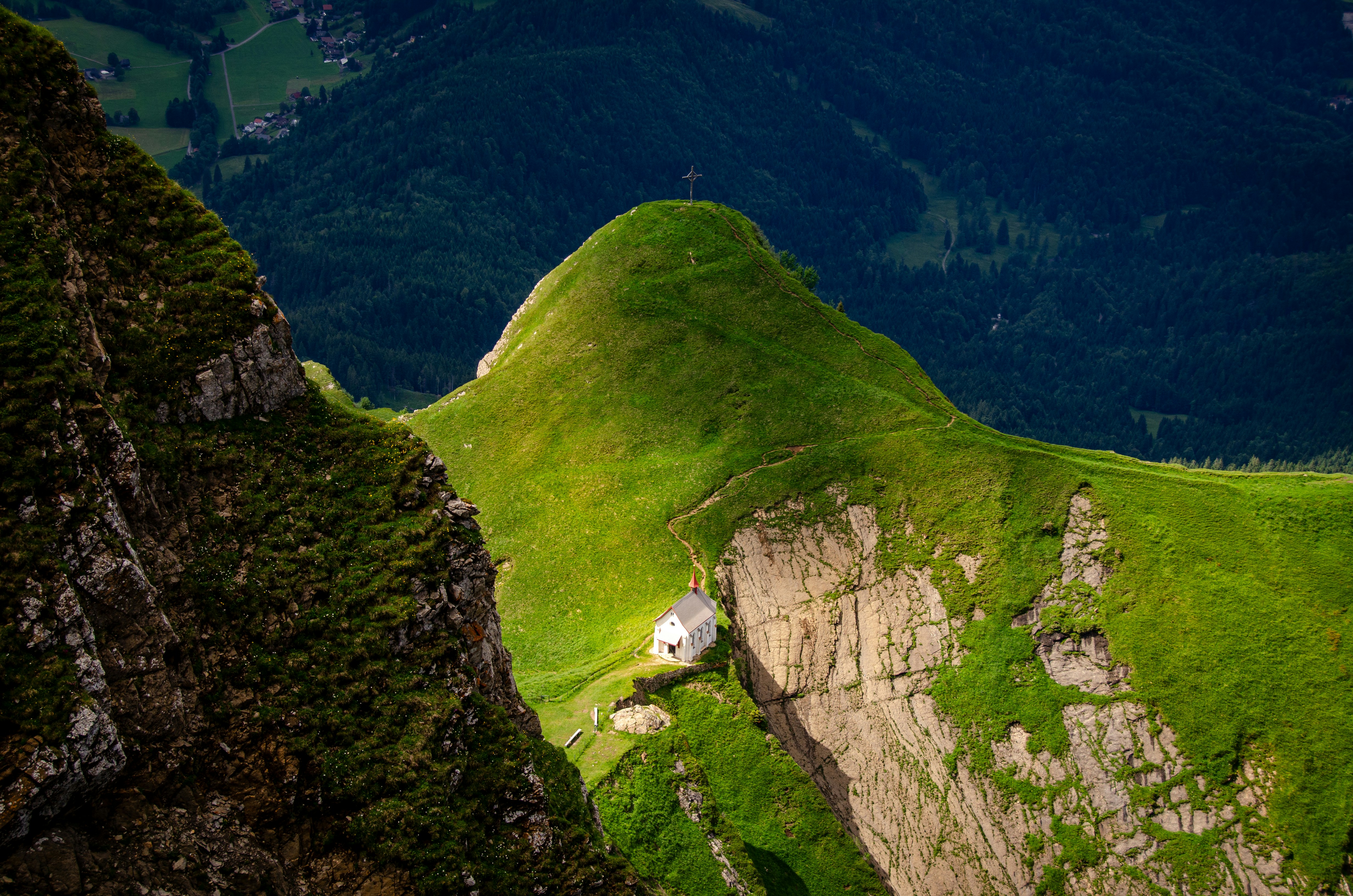 Ein grüner Berg mit einem weißen Haus auf dem Gipfel
