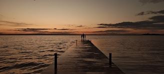 A long dock with a sunset in the background