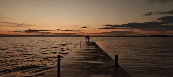 A long dock with a sunset in the background